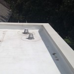 A roof with two metal vents on it.