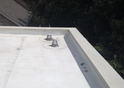 A white roof with two metal vents on it.