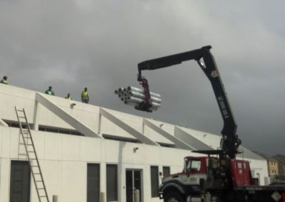 A crane lifting pipes onto a roof of a building